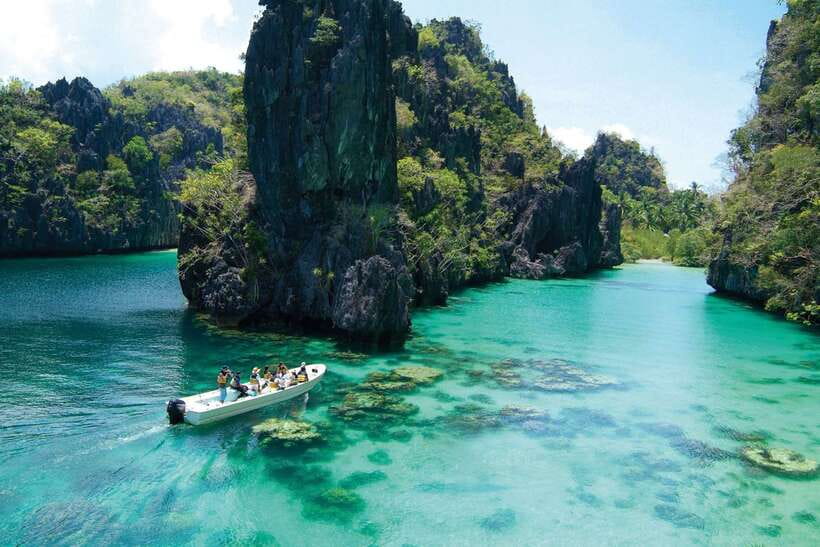 An outrigger bangka moored under limestone cliffs in a lagoon at El Nido, Palawan